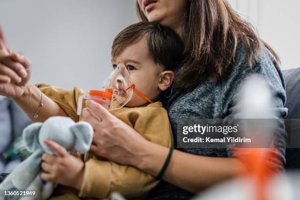 baby boy taking inhalation treatment at home. - asthma inhaler child stock pictures, royalty-free photos & images