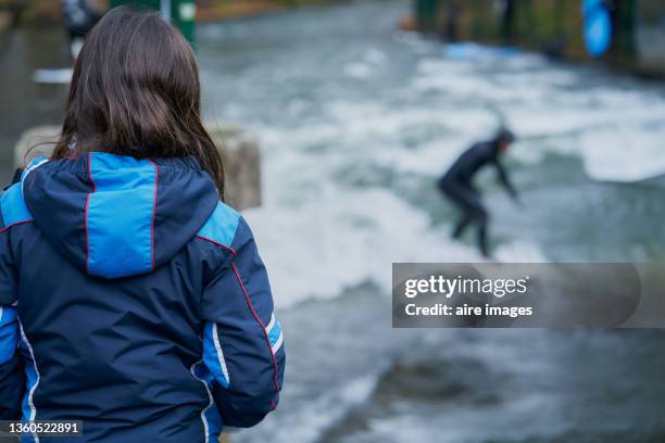 girl on his back watching a surfer in eisbach, munich, bavaria, germany - eisbach river stock pictures, royalty-free photos & images