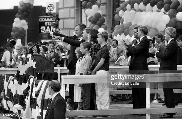 View of America politician George HW Bush and married couple, Dan Quayle & Marilyn Quayle, along with others, wave from a podium during a campaign...