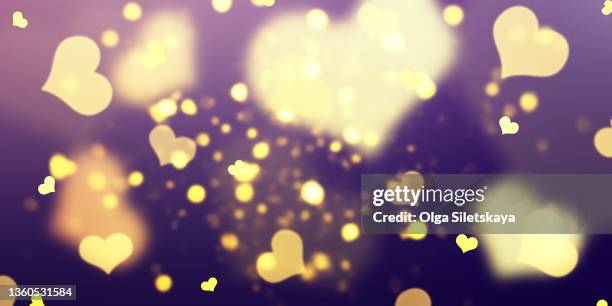 gold defocused heart shaped lights on purple background - gold heart stock-fotos und bilder