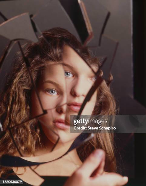 Portrait of teenaged Ukrainian actress and supermodel Milla Jovovich, her image reflected in a cracked mirror, Los Angeles, California, 1988.
