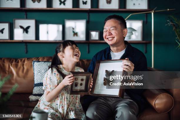 happy asian grandfather holding insect collection specimen holder and granddaughter holding plant and seeds specimen holder at home, sharing their common interests and hobbies, chatting joyfully. multi-generation family. hobbies and interests concept - collect stock pictures, royalty-free photos & images