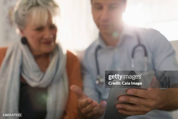 male doctor showing digital tablet to patient - flouté photos et images de collection