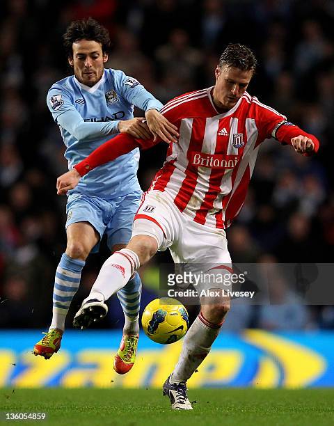 Robert Huth of Stoke City tangles with David Silva of Manchester City during the Barclays Premier League match between Manchester City and Stoke City...