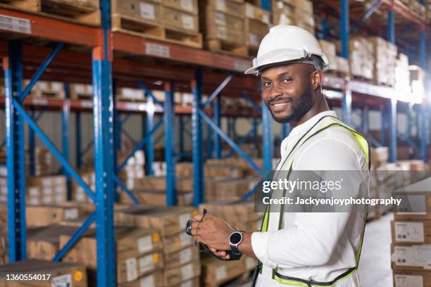 warehouse worker standing in large warehouse, while counting inventory of material stock in factory. - warehouse worker stock-fotos und bilder