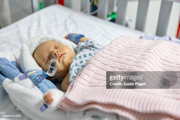baby girl recovering in hospital cot just after major surgery - gal stockfoto's en -beelden