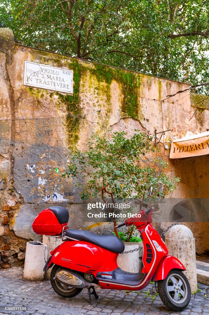 Ein charakteristischer Vespa-Roller, der in einer Gasse von Trastevere im historischen Herzen Roms geparkt ist