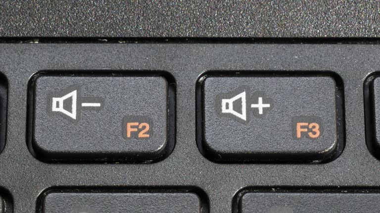 Computer Volume Button Man turning up the volume on a laptop keyboard, finger pressing the vol ...