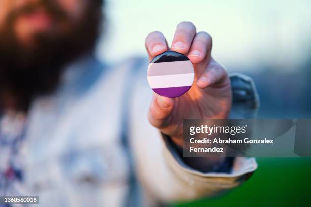 an unrecognizable person holding and showing a pin with agender colors flag - brooch stock pictures, royalty-free photos & images