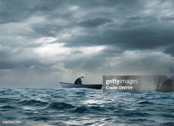 dejected man sitting in sinking row boat - rowboat stock pictures, royalty-free photos & images