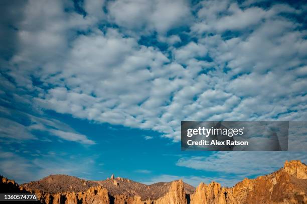 high altitude cirrocumulus clouds high above a mountanous desert area - cirrocúmulo fotografías e imágenes de stock