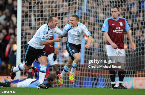 Richard Dunne of Aston Villa looks dejected as Craig Bellamy of Liverpool celebrates scoring to make it 1-0 with Charlie Adam during the Barclays...