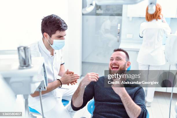 laughing male ready for teeth fixing at dentist's clinic - funny surgical masks stockfoto's en -beelden