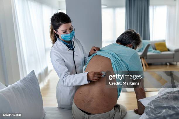young female doctor examining senior men at home - exhaling stock pictures, royalty-free photos & images