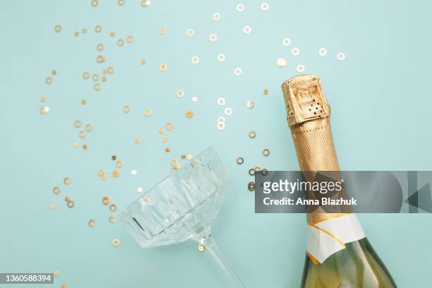 champagne bottle and golden shiny confetti over blue background, trendy greeting card for holidays and celebrations. - birthday flag stock-fotos und bilder