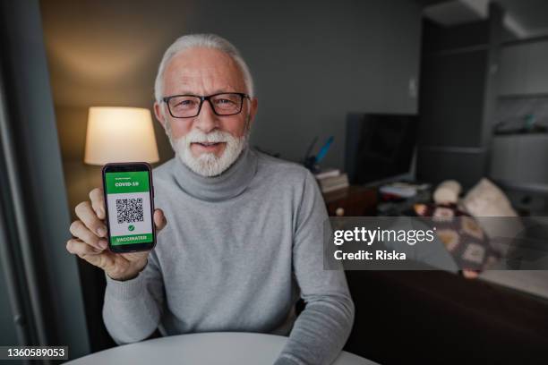 homme âgé montrant un certificat de vaccination au téléphone - man showing phone photos et images de collection