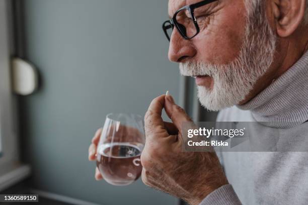senior man taking a medical pill - aspirina imagens e fotografias de stock