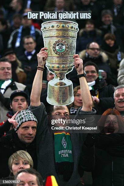 Fan of Gladbach shows a copy of the DFB Cup trophy during the DFB Cup round of sixteen match between Borussia Moenchengladbach and FC Schalke 04 at...