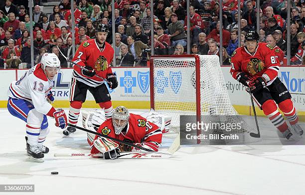 Michael Cammalleri of the Montreal Canadiens turns toward the puck as Chicago Blackhawks goalie Corey Crawford sprawls out onto the ice and Brent...