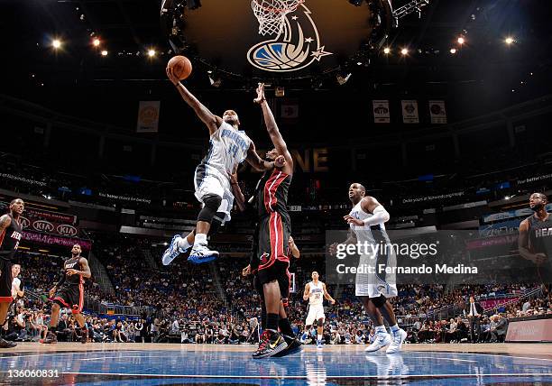 Jameer Nelson of the Orlando Magic shoots the basketball against Chris Bosh of the Miami Heat during the preseason game on December 21, 2011 at Amway...