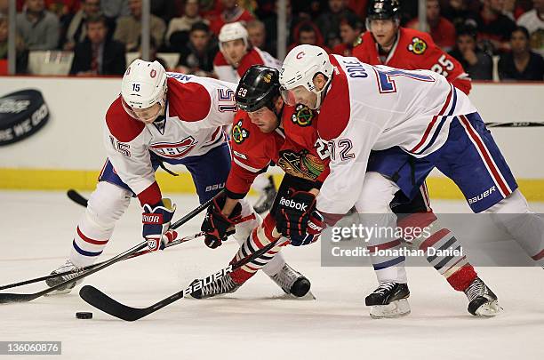Bryan Bickell of the Chicago Blackhawks battles for the puck with Petteri Nokelainen and Erik Cole of the Montreal Canadiens at the United Center on...