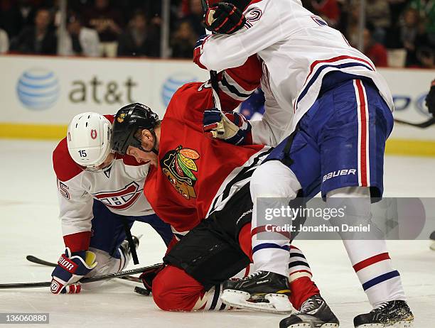 Bryan Bickell of the Chicago Blackhawks is held by Erik Cole of the Montreal Canadiens as he eyes the puck with Petteri Nokelainen at the United...