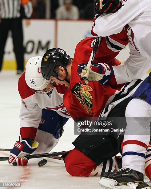 Bryan Bickell of the Chicago Blackhawks is held by Erik Cole of the Montreal Canadiens as he eyes the puck with Petteri Nokelainen at the United...