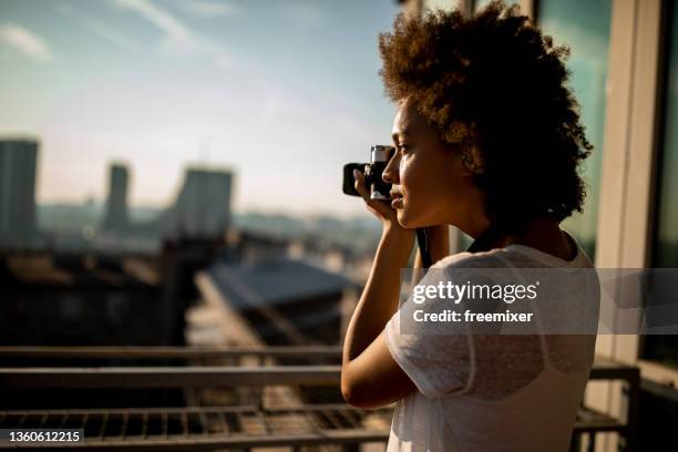 mixed race woman standing on balcony and taking a photography - spiegelreflexcamera stockfoto's en -beelden