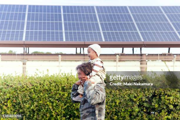 a senior man laughs as he carries a baby boy on his shoulders. - fuel and power generation stock-fotos und bilder