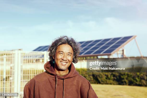 a portrait of a senior man standing in a place where he can see the solar panels. - environmentalist stock pictures, royalty-free photos & images