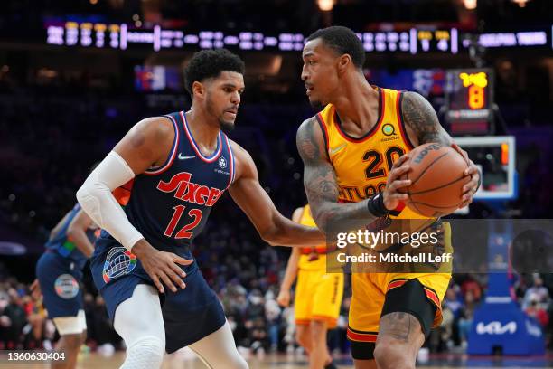 Tobias Harris of the Philadelphia 76ers guards John Collins of the Atlanta Hawks at the Wells Fargo Center on December 23, 2021 in Philadelphia,...