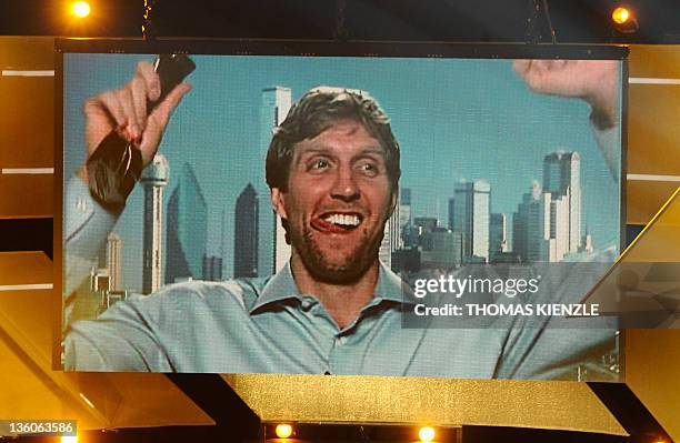 Basketball player Dirk Nowitzki is seen on a giant screen celebrating with the trophy of Germany's Athlete of the Year 2011 during a satelite...