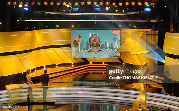 Basketball player Dirk Nowitzki is seen on a giant screen celebrating with the trophy of Germany's Athlete of the Year 2011 during a satelite...