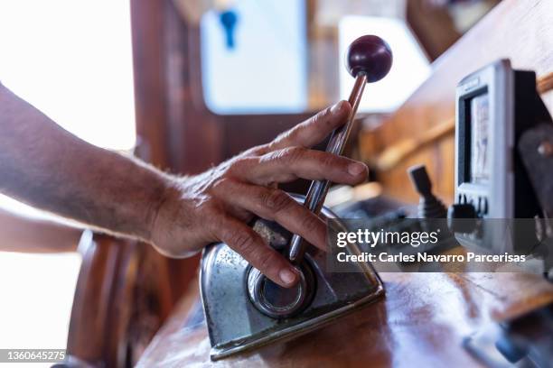 hand of a male pushing a lever while driving a boat - levier de contrôle photos et images de collection