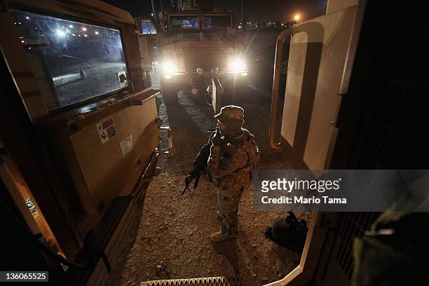 Soldier from the 3rd Brigade, 1st Cavalry Division waits to depart outside a Mine Resistant Ambush Protected vehicle in the last convoy from Iraq at...