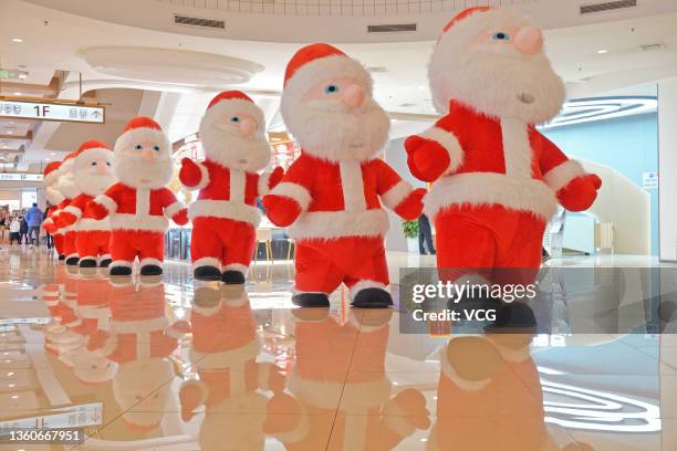 Workers wearing inflated costumes of Santa Claus entertain customers at the Joy City shopping mall on December 24, 2021 in Yantai, Shandong Province...