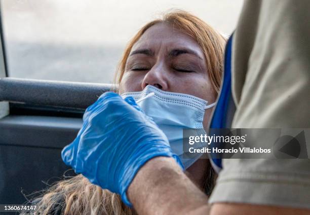 Woman closes her eyes as a health technician performs a nasal swab for an antigen COVID-19 test on a bus converted into a mobile test facility in...