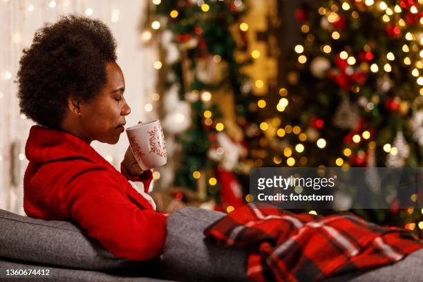 woman enjoying the christmas holidays by relaxing on the sofa with a cup of tea - christmas mug stock pictures, royalty-free photos & images