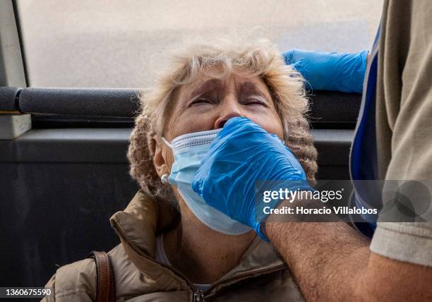 Woman grimaces as a health technician performs a nasal swab for an antigen COVID-19 test on a bus converted into a mobile test facility in Mercado da...