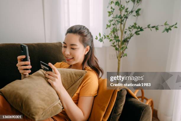 jeune femme utilisant le paiement par carte de crédit - phone credit card photos et images de collection