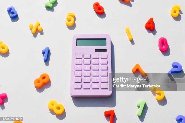 purple calculator and math symbols on a universal gray background. gray background. magenta calculator. math symbols. - fun calculator stockfoto's en -beelden