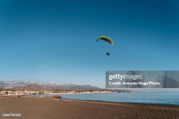 unrecognizable person practicing powered paragliding on a beach - motor paraglider stock pictures, royalty-free photos & images