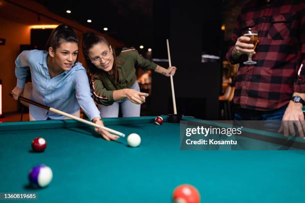 um grupo de amigos se divertindo jogando bilhar em um bar no centro da cidade. - snooker - fotografias e filmes do acervo