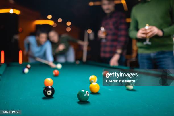 en el primer plano hay bolas de billar, mientras que en el fondo hay un grupo de personas jugando al billar. fondo borroso - pool table fotografías e imágenes de stock