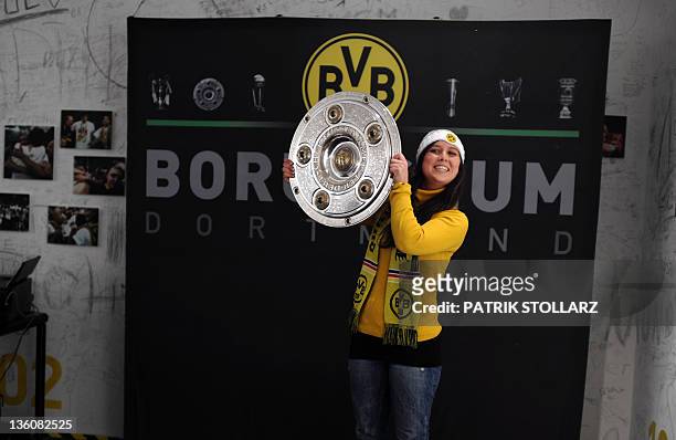 Fan of the German football club Borussia Dortmund poses with the trophy of the German Football League Bundesliga which Dortmund won during the last...
