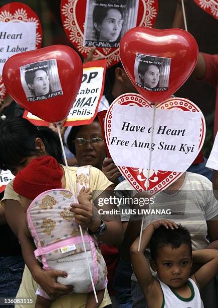 Filipino human rights activists with heart-shaped placards and baloons kiss a poster of Detained Burmese rights activist, Aung San Suu Kyi during a...