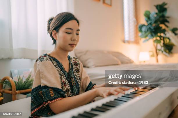 home alone keyboard piano hobby young woman practicing piano. - asian pianist stock pictures, royalty-free photos & images