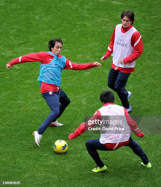 Yossi Benayoun is closed down by Tomas Rosicky and Ryo Miyaichi of Arsenal during a training session at the Emirates Stadium on December 23, 2011 in...