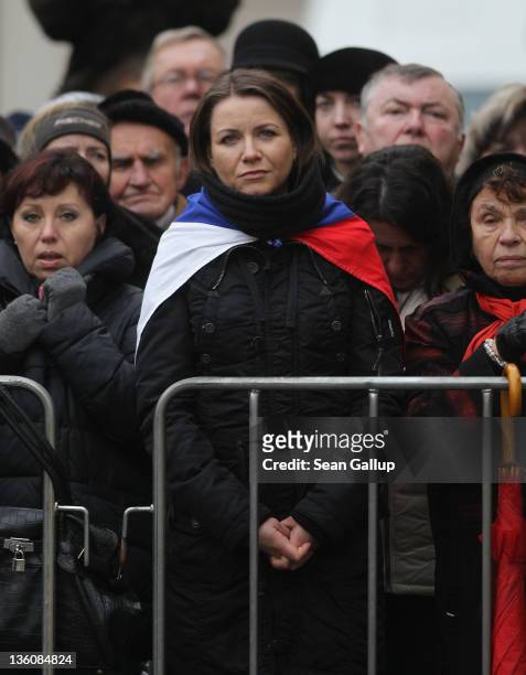 Mourners, including a woman draped in a Czech flag, watch the state funeral of former Czech President Vaclav Havel transmitted live onto large-screen...