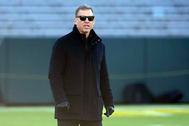 Troy Aikman walks across the field before the game between the Cleveland Browns and the Green Bay Packers at Lambeau Field on December 25, 2021 in...